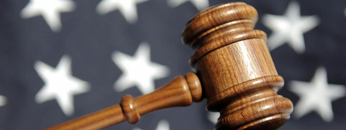 A gavel is in the foreground, with a United States flag in the background. 